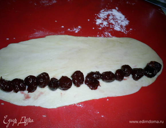 Разделить тесто на 23 части. Из каждой раскатать прямоугольник приблизительно 25*10 см. По длинному краю выложить ряд вишенок.