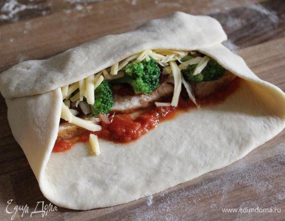 Завернуть короткие края теста на начинку, а затем по длинной стороне свернуть рулет. 