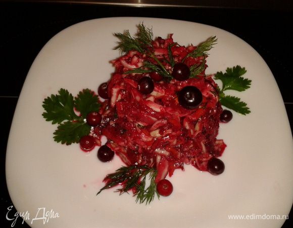 Свеклу сырую через  терку, добавить чеснок через терку, все смешать  с капустой, заправить подсолнечным маслом, украсить клюквой и зеленью.