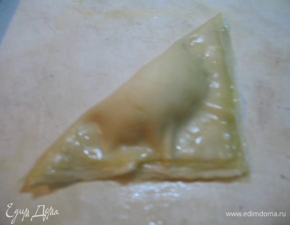 Складываем треугольником, слегка придавив возле начинки. Выкладываем на выстеленный пергаментом противень.