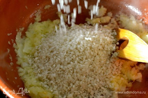 Как только лук станет прозрачным (не зажаривать!), добавить рис. Перемешать и пару минут дать рису напитаться луковым ароматом.