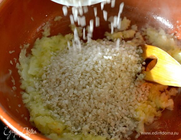 Как только лук станет прозрачным (не зажаривать!), добавить рис. Перемешать и пару минут дать рису напитаться луковым ароматом.