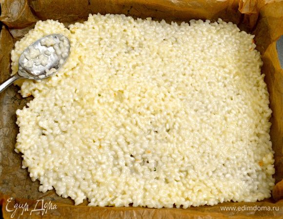 Рис поделить визуально на двое. Выложить по дну формы тонким слоем первую часть риса. Разровнять ложкой.