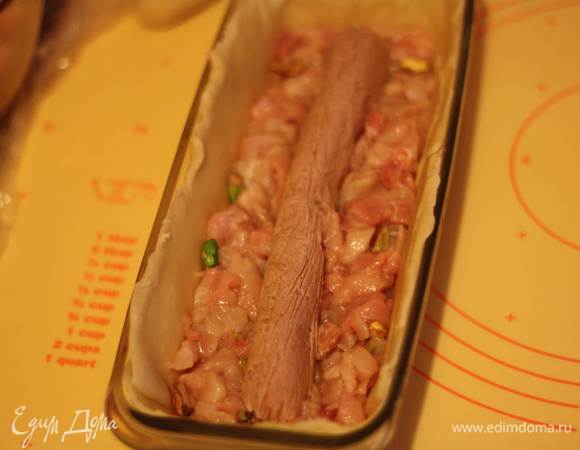 Выкладываем мясо до половины формы, кладем колбаску из паштета, слегка вдавливаем ее и выкладываем остальное мясо.