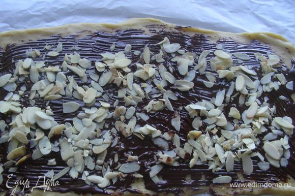 Тесто покрываем частью растопленного шоколада и посыпаем миндальными лепестками.
