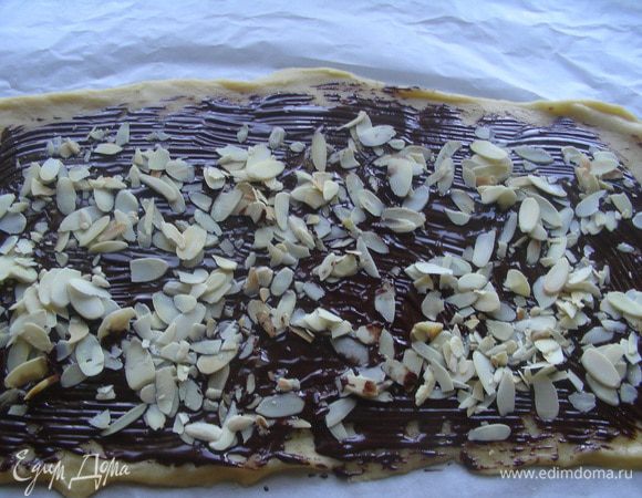 Тесто покрываем частью растопленного шоколада и посыпаем миндальными лепестками.
