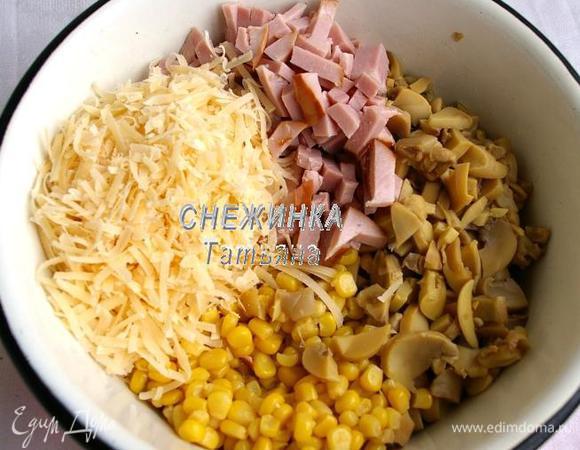 Ветчину и шампиньоны нарезаем небольшими кусочками, кубиком или соломкой. Шампиньоны у меня были консервированные, но не маринованные, можно взять и свежие, только предварительно отварить в подсоленной воде. Сыр натираем на крупной тёрке. Соединяем всё в миске. Открываем банку кукурузы, сцеживаем жидкость и добавляем к остальным ингредиентам.