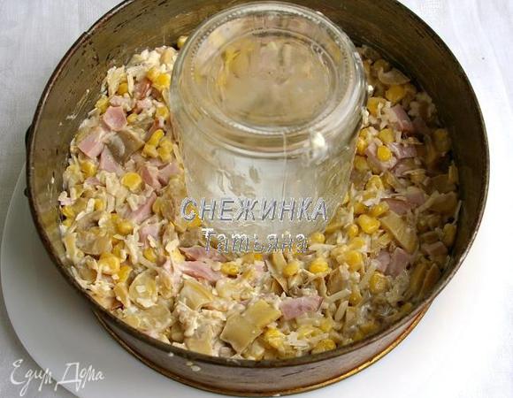 Добавляем молотый чёрный перец, пропущенный через пресс чеснок, перемешиваем, заправляем салат майонезом, его количество берите по вкусу. Теперь берём кольцо от разъёмной формы и ставим на тарелку. У меня диаметром 21 см. В центр ставим стакан или как я пустую банку 450 мл. Между банкой и кольцом выкладываем салат и хорошо утрамбовываем, чтобы когда мы извлечём вспомогательные предметы, салат держал форму.