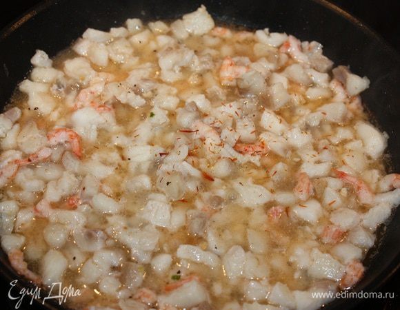 На сковородку налить оливковое масло и добавить чеснок, затем филе, креветки, соль и перец по вкусу. Затем добавляем 100 мл шампанского и шафран. Тушим около 5 минут. 