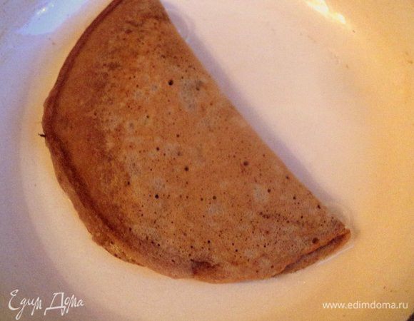 Сразу же, пока блин не схватился, выложить немного вишневой начинки на одну сторону блина, оставив свободными края.