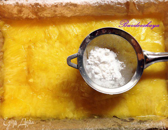 Жаропрочную форму застелить пергаментом и выложить на нее слой нарезанных ананасов, смазать при помощи силиконовой кисточки соком имбиря и немного присыпать сахарной пудрой. Таким же образом проделываем с оставшимися ананасами, промазывая каждый слой соком и присыпая пудрой !