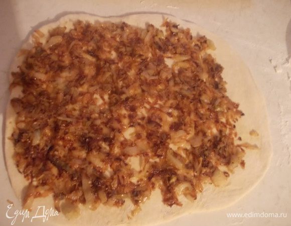 Когда тесто подойдет,хорошенько его помять(подсыпать муки) и раскатать в квадрат,толщиной около 1 см. Предварительно потушить капусту с луком на растительном масле,добавить соль и специи по вкусу. Укладываем остывшую начинку,на пласт теста.