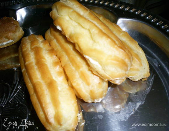 Охлажденные эклеры наполняем кремом. Можно при помощи кондитерского мешка, а можно аккуратно срезать донышко острым ножом и затем наполнить кремом, используя чайную ложку. Донышко осторожно приклеиваем на место.