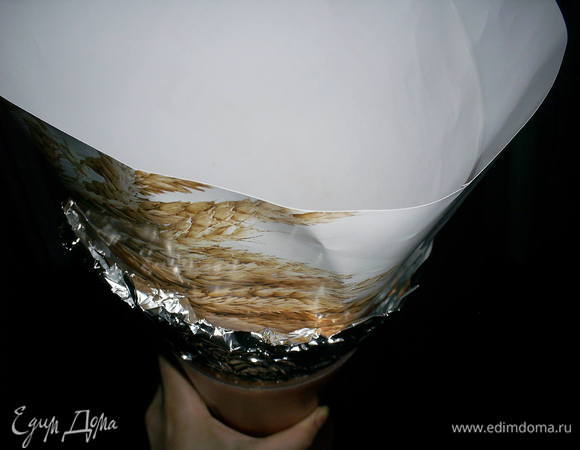 Конус из профитролей можно выкладывать на блюдо традиционным способом, начиная с самого широкого яруса, и постепенно уменьшать количество профитролей в каждом слое. Однако есть вероятность, что конструкция получится кривоватой (у меня так и было в первый раз) или развалится до застывания глазури. Поэтому из плотной бумаги делаем большой конус, склеиваем его скотчем. Чтоб облегчить процесс вынимания готового торта, внутренность конуса лучше выложить пищевой пленкой или фольгой. Я этого не сделала и усложнила себе процесс извлекания готового торта из конуса-формы. Готовый конус помещаем верхушкой вниз в любую подходящую емкость, которая будет его ровно держать. Я использовала большую вазу.