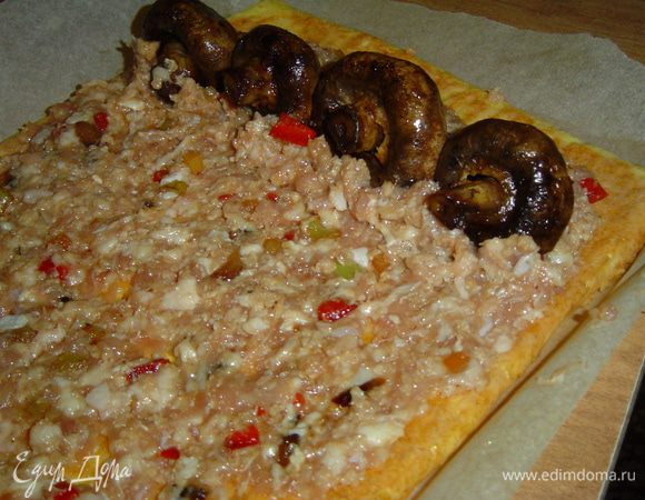 Достаем корж с противня, бумагу не снимаем, сверху равномерно распределяем фарш, а на один конец кладем обжаренные грибы,