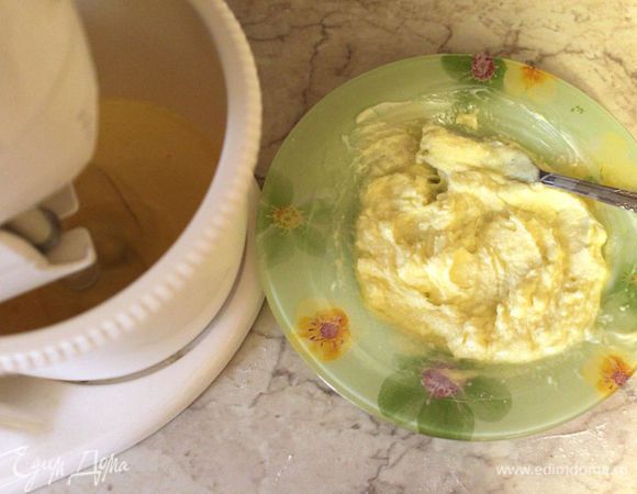 Разогреть духовку до 160 градусов. Взбить яйца с половиной сахара для коржа​​ в пышную массу. Размягченное сливочное масло растереть с оставшейся частью сахара, добавить к яйцам, взбить, добавить ванильный концентрат или эссенцию.