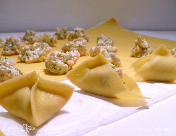 Пока соус утушивается, раскатываем тесто, режем на квадраты. В центр квадрата помещаем чайную ложку сырно-рыбной смеси. С помощью кисточки наносим желток на края теста. Сперва соединяем два друг напротив друга лежащих конца. Затем защипываем третий и четвёртый уголки.
