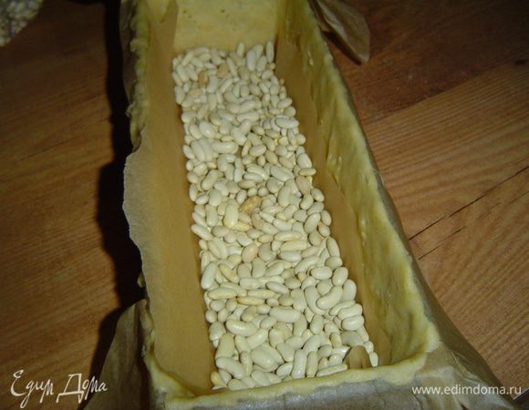 Тесто достаем из холодильника и равномерно распределяем по форме (прямоугольная 30*12), застеленной пергаментной бумагой. Тесто накалываем вилкой, сверху застилаем пергаментной бумагой, а сверху насыпаем фасоль. Отправляем корж в духовку на 10 минут при температуре 200 гр., затем убираем пергамент с фасолью, уменьшаем температуру до 180 гр. и выпекаем корж еще 10 минут. 