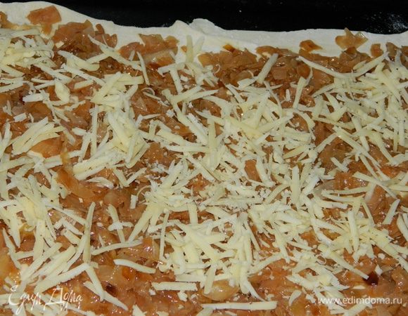 Слоеное тесто разморозить. Один пласт теста тонко раскатать, переложить в форму для выпечки (например на лист), выложить на него тушеную капусту, сверху посыпать тертым сыром.