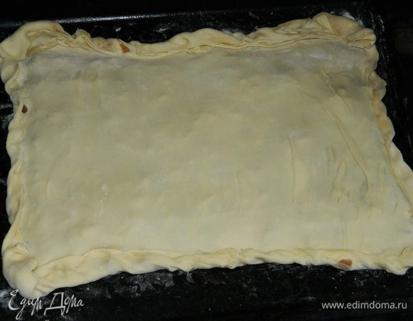 Второй пласт слоеного теста тонко раскатать, накрыть сверху пирог, края защипнуть.