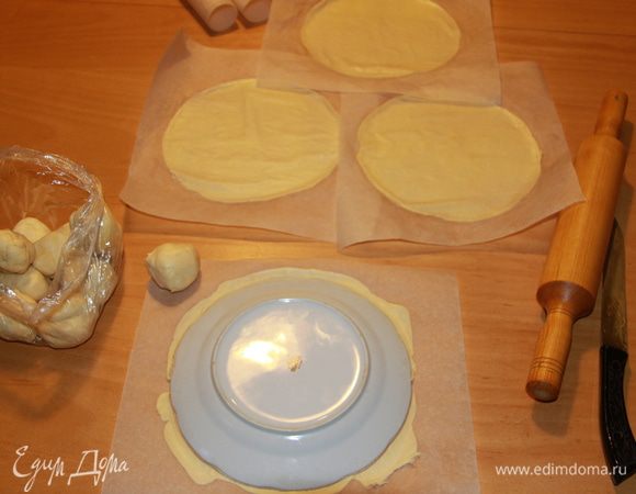 Из холодильника достать отдохнувшее тесто. Разделить тесто на 16 колобков (раньше как-то не считала, сколько выйдет - столько и выйдет, а потом услышала по ТВ, что в правильном "Наполеоне" должно быть именно 16 коржей). Каждый колобок раскатать в пласт толщиной 2 мм, лучше сразу на бумаге для выпечки, очертить по тарелке желаемого диаметра.