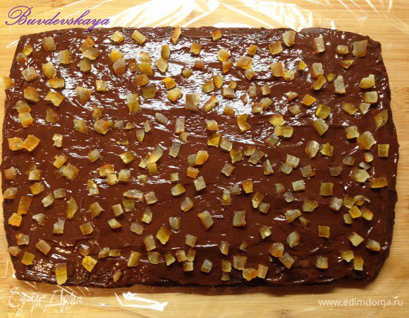 Бисквит для полена выложить на пищевую пленку, пропитать апельсиновым сиропом. Выложить на бисквит примерно половину крема и разровнять силиконовой лопаткой, сверху выложить нарезанные цукаты. Свернуть бисквит в рулет (по широкой стороне), как можно плотнее, помогая себе пищевой пленкой. Завернуть рулет в пищевую пленку и отправить охлаждаться в холодильник минимум на 2 часа.