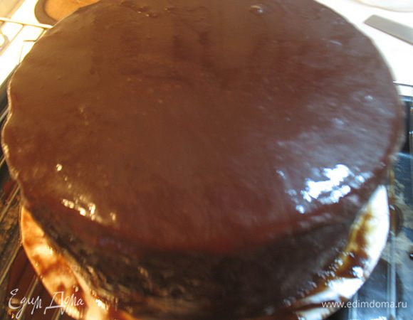 Достаем из морозилки торт, ставим на решетку и сразу покрываем глазурью.  Выливаем часть глазури, позволяем ей самой растечься по поверхности. Можно немного прокрутить торт. Даем немного постоять и выливаем еще часть глазури. Убираем в холодильник. 