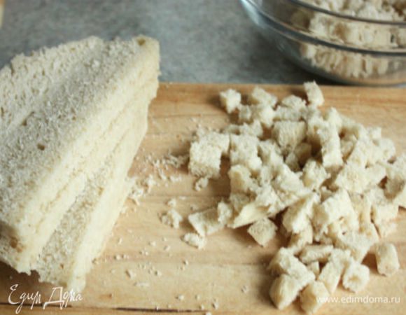 Растопить в сковороде 10 г сливочного масла, добавить бекон, затем 1/3 лука и слегка обжарить в течении 5 мин., остудить.
Хлеб без корок порезать маленькими кубиками, положить в миску.
