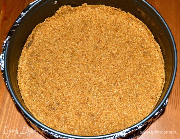 Полученную мокрую крошку утрамбовать в дно разъемной формы диаметром 23 см. Выпекать в разогретой до 170 С духовке 10 минут. Готовый корж достать из духовки, а температуру в духовке повысить до 220 С. 