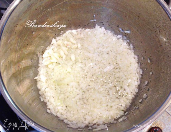 Лук и чеснок мелко-мелко порезать. Разогреть в кастрюле с толстым дном оливковое масло и выложить лук с чесноком. Тушить до размягчения на небольшом огне. 
