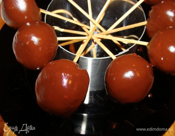 В это время растопить на водяной бане шоколад, можно добавить кусочек сливочного масла (50 г). Шарики нанизать на шпажки, обмакнуть в шоколад, поставить стекать. Как только все шарики окажутся в шоколаде, убрать конструкцию полностью в морозилку еще на 15 минут. Хранить конфетки в холодильнике. 