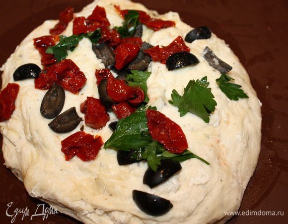 Дрожжи растворить в теплой воде. Добавить соль, сахар, базилик, муку и замесить тесто. Выложить его на силиконовый коврик, смазанный оливковым маслом. Добавить 2 ст. ложки оливкового масла, порезанные вяленые помидоры, маслины и петрушку. 