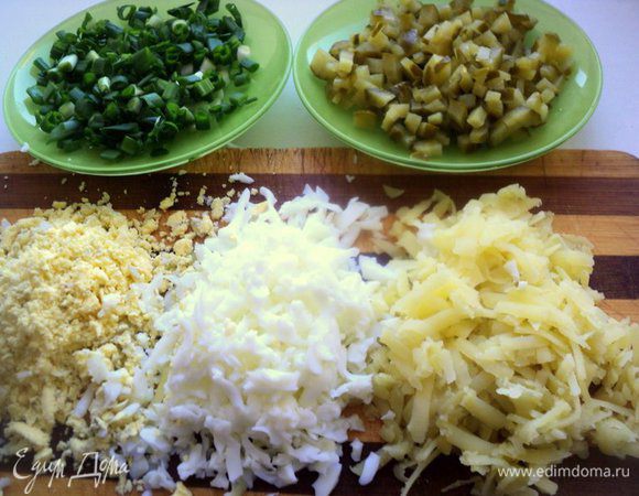 Отварить картофель в мундире и яйца. Почистить от кожицы и скорлупы. Картофель натереть на терке, яйца разделить на белки и желтки и тоже натереть. Зеленый лук и огурец мелко нарезать.