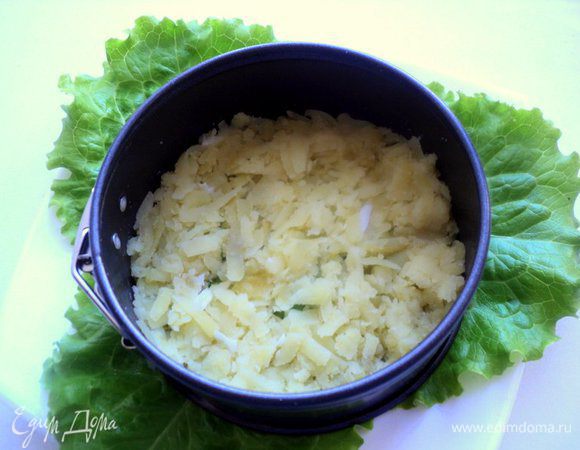 На тарелку выложить листья салата, сверху металлическое кольцо (у меня Ф-10 см). На дно выложить натертый картофель, посолить и поперчить по вкусу.