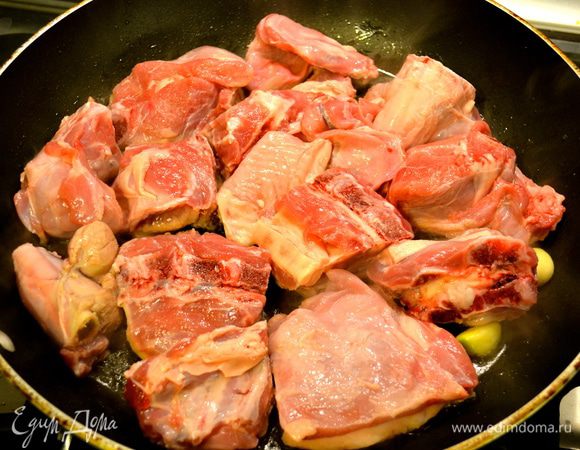 Духовку включить на 200°С. В глубокой тяжелой сковороде разогреть оливковое масло и жир. Положить чеснок и розмарин. Добавить мясо.  