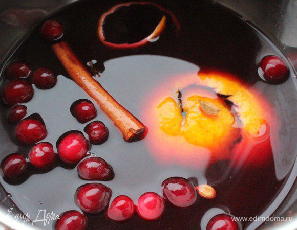 Налить в вино в кастрюлю, положить в него кардамон (раздавить стручки ножом), гвоздику, душистый перец и палочку корицы. Добавить клюкву,  апельсиновую и лимонную корки. Медленно прогреть на самом слабом огне. Не кипятить!!! Снять с огня и охладить. Добавить мед (или сахар). Готовый охлажденный глинтвейн процедить.