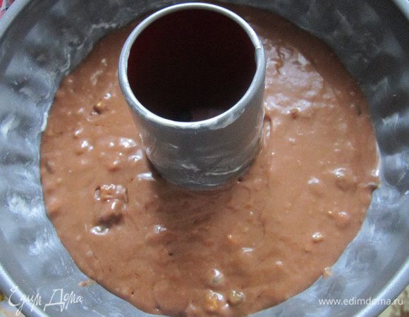 Подготовить изюм и орехи. Изюм промыть и высушить, орехи порубить в крошку и добавить в тесто. В смазанную маслом форму выложить тесто. Выпекать в заранее разогретой до 180-200°С духовке около 1 часа. 