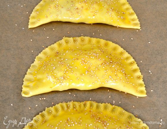 Украсить край каждого пирожка и выложить их на противень (у меня получилось два противня по три пирожка на каждом). Смазать пирожки оставшимся яйцом и присыпать кунжутными семенами. Выпекать в центре духовки 20 минут, пока тесто не покроется золотистой корочкой. 