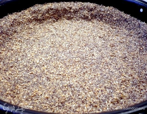 Печенье покрошим. Для коржа смешаем 75 г мака с крошкой из печенья и добавим мягкое сливочное масло. Вымесим до однородности и добавим в получившуюся крошку 2 ст.л. холодной воды. Выложим тесто в смазанную маслом форму диаметром 24 см, образуя достаточно высокие бортики. Уберем форму в холодильник на полчаса.