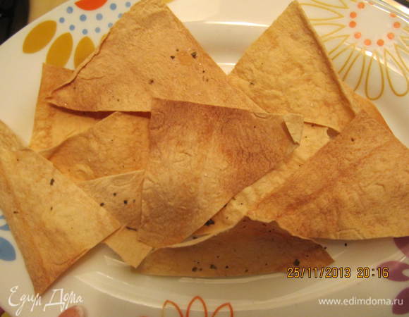 Включаем духовку. Чипсы. Кухонными ножницами нарезаем 1 лист лаваша на треугольники. Присыпаем солью, смесью перцем и базиликом. Отправляем в духовку на 5 минут. 