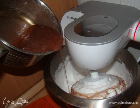 Снижаем скорость миксера. Тонкой струйкой вливаем еще горячий сироп. 