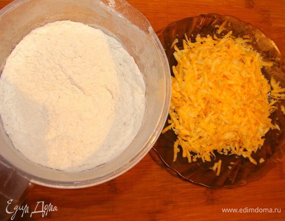 Сыр натеререть на терке. Муку просеять, смешать с солью, разрыхлителем, сахаром и куркумой. Добавить к муке сыр, перемешать.