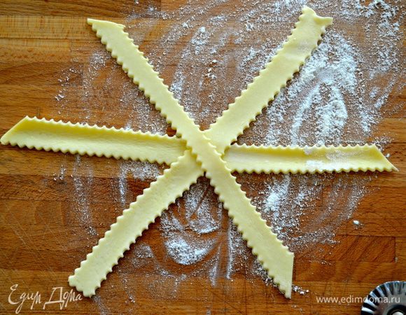 Духовку включить на 200°С. Противень застелить пекарской бумагой. Слоеное тесто нарезать полосочками шириной примерно 1 см. Выложить три полосочки вот таким образом, как на фото.