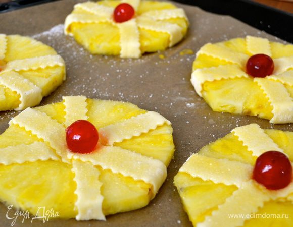 Выложить получившиеся пирожные на противень, смазать слегка взбитым яйцом и посыпать сахаром. В центр каждого положить по вишенке.