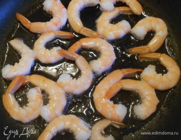 В глубокой сковороде нагрейте масло и слегка обжарьте креветки. 