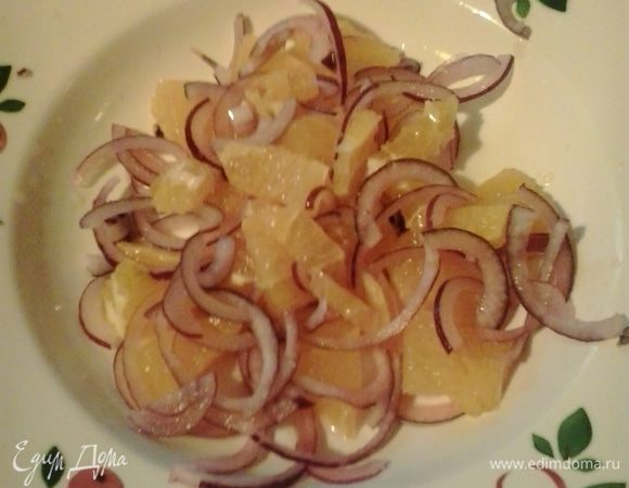 Апельсин очищаем и нарезаем средним кубиком. Сок, выделяющийся при нарезке апельсина, выливаем в заправку. Лук нарезаем полукольцами. В салатник складываем апельсин и лук.