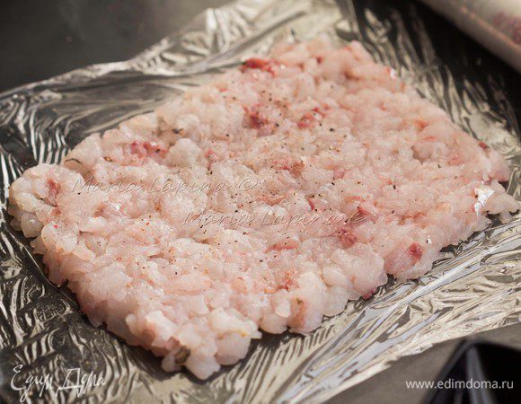 На столе выкладываем слой пищевой пленки. "Тяпаное" филе кладем сверху одним слоем, оставляя место с боков. Солим и перчим филе. 