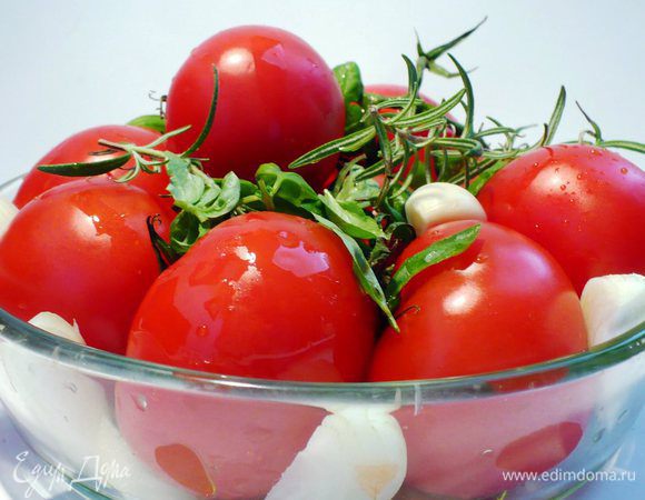 Помидоры вымыть, слегка обсушить, отправить в форму для запекания. Базилик и розмарин также промыть, обсушить и добавить к помидорам. Чеснок и лук почистить, нарезать дольками, распределить между помидорами. Посыпать солью, слегка сбрызнуть оливковым маслом и запекать около 30 минут при 200°C.