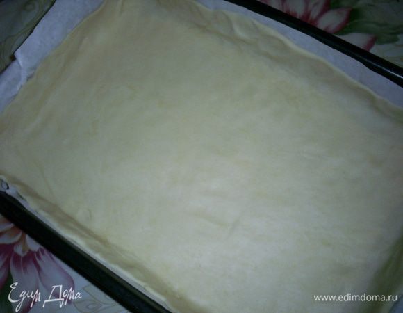 Тесто раскатываем в тонкий пласт. Удобно это делать прямо на бумаге для выпечки. Затем вместе с бумагой перекладываем тесто в форму для выпекания.