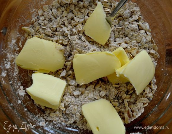 Добавить холодное масло кусочками. Помогая себе вилкой, руками втереть масло в сухую смесь.